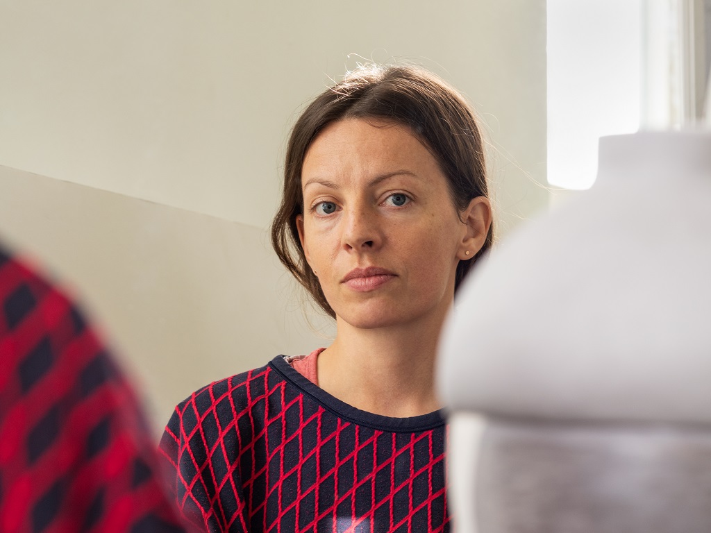 Anna Lea Hucht Porträt der Künstlerin Anna Lea Hucht in einem rot-blauen Oberteil, sie blickt ruhig in die Kamera.