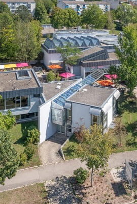 Luftaufnahme der Kunsthalle Tübingen mit ihrem modernen, flachgebauten Gebäudekomplex, umgeben von Bäumen und Grünflächen, eingebettet in ein Wohngebiet.