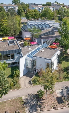 Luftaufnahme der Kunsthalle Tübingen mit ihrem modernen, flachgebauten Gebäudekomplex, umgeben von Bäumen und Grünflächen, eingebettet in ein Wohngebiet.