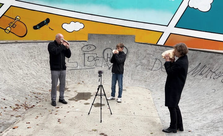 Kathleen Jahn sowie Lutz und Augustin Mandler spielen Schneckenhörner in einem Skatepark in Göppingen; ein Mikrofon steht zwischen ihnen. Die Aufnahme entstand während der Performance „Kathleen Jahn. FREQUENZEN“.