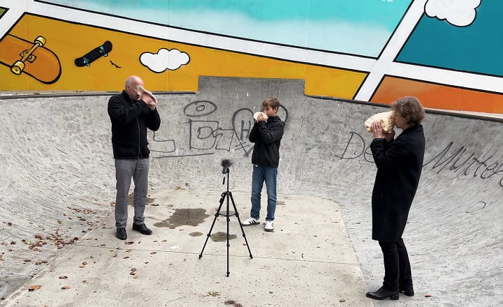 Kathleen Jahn sowie Lutz und Augustin Mandler spielen Schneckenhörner in einem Skatepark in Göppingen; ein Mikrofon steht zwischen ihnen. Die Aufnahme entstand während der Performance „Kathleen Jahn. FREQUENZEN“.