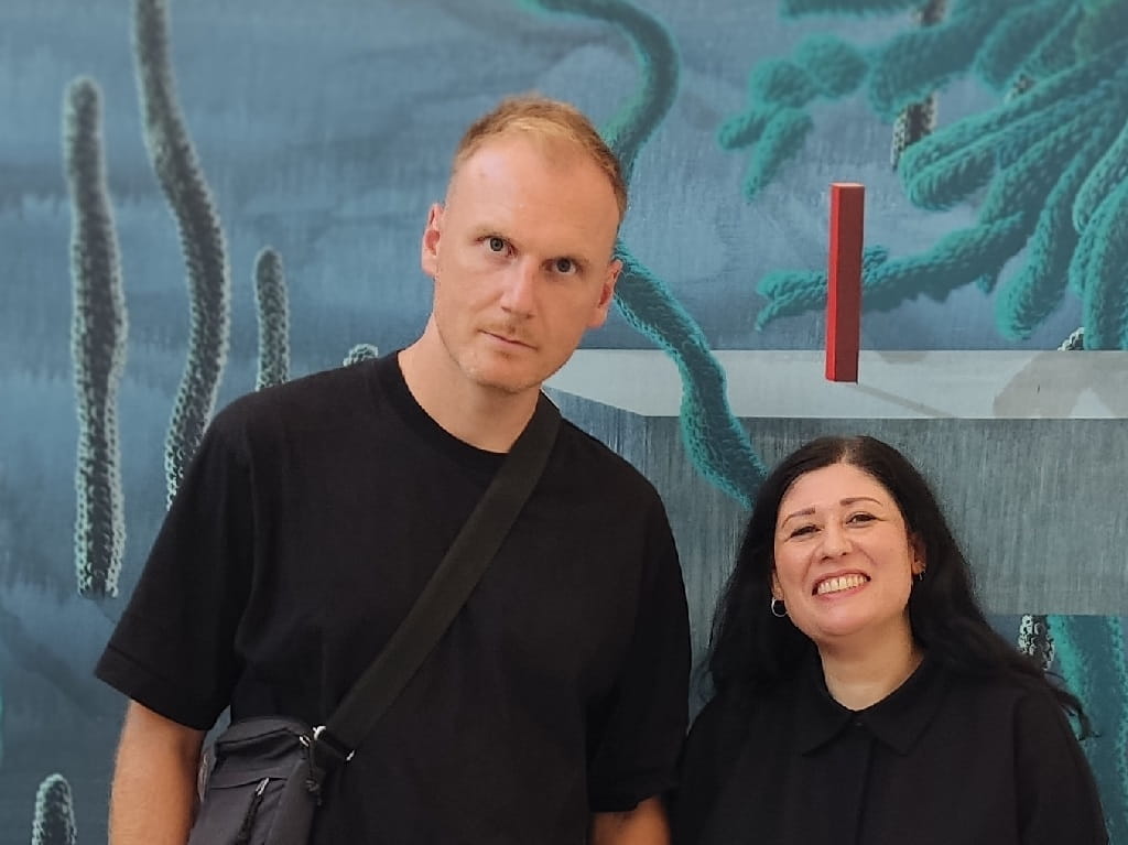 Leo Staigle und Katia Fazio bei der Eröffnung der Jahresausstellung 2026. Porträt von Leo Staigle und Katia Fazio vor einem großformatigen Kunstwerk, beide blicken in die Kamera.